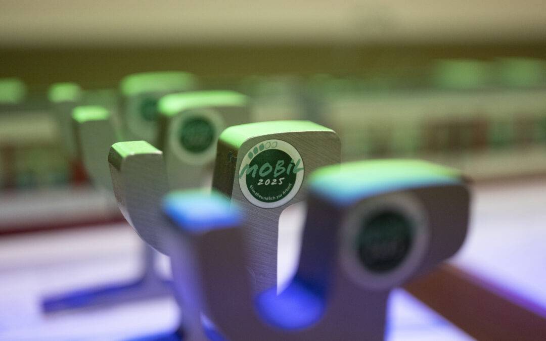 Close-up of metal tokens with green tops, one shows a circular sticker reading 'MOBI 2025'.