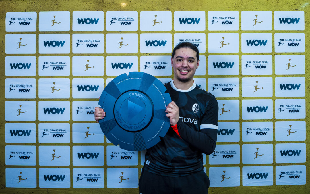 Athlete in uniform smiles while holding a large blue circular trophy in front of a WOW Grand Final backdrop.