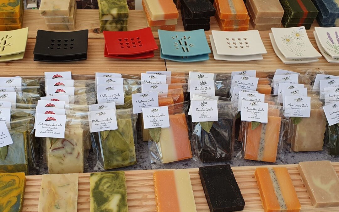 Assorted colorful handmade soaps stacked on a wooden rack with price tags showing 4,00 € in front.