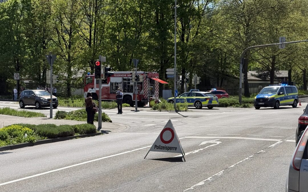 Emergency scene at an intersection with a red fire truck, police cars, and officers guarding a blocked street.