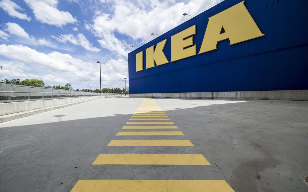 Blue IKEA warehouse exterior with a large yellow IKEA logo and yellow ground markings in the foreground.
