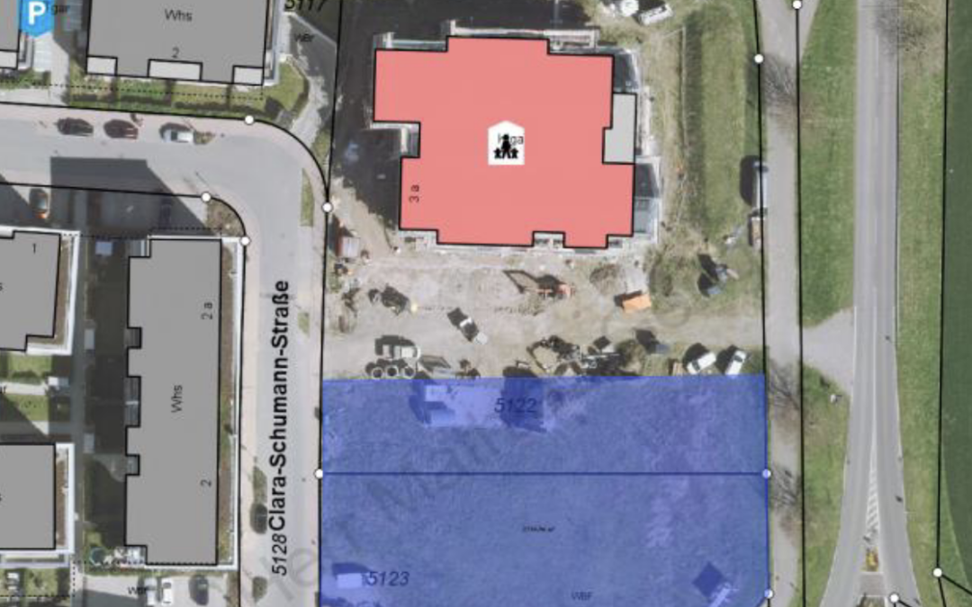Aerial site map showing a red building, a large blue parcel to the south, and surrounding streets and compass rose at top left