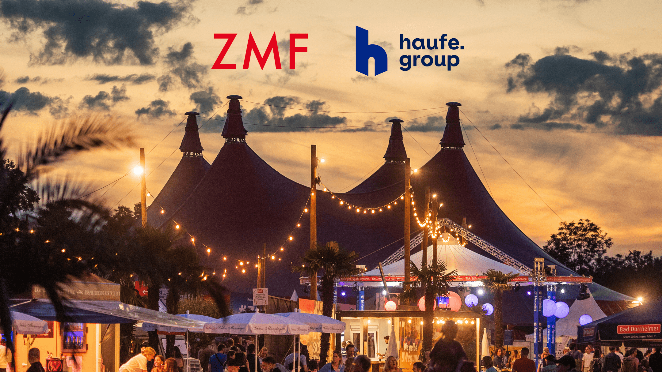Festival scene at sunset with large tents and string lights; prominent ZMF and haufe group logos in the sky above the crowd.
