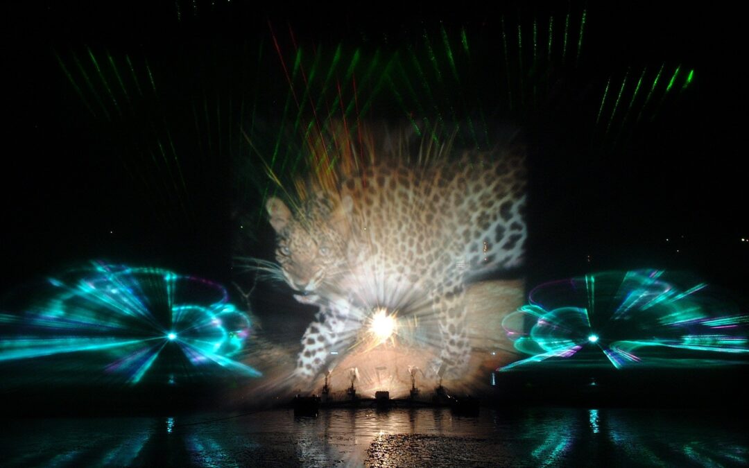 Nighttime fountain show with a leopard-print projection across a large screen and colorful laser lights over water.