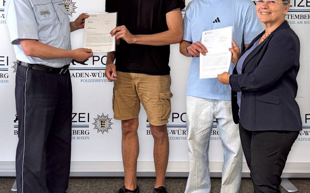 Police officer presents a certificate to a young man, flanked by two youths and a smiling woman, in front of a Baden-Württemberg Police backdrop.