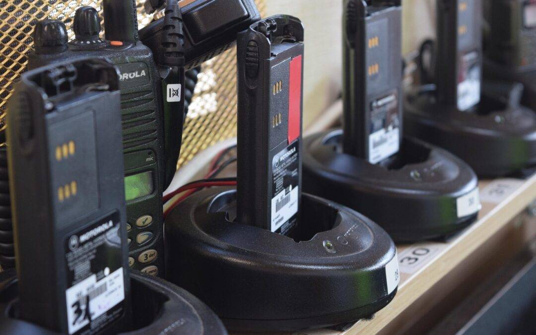 Row of Motorola handheld radios in their charging docks on a store shelf, labeled with numbers in the foreground