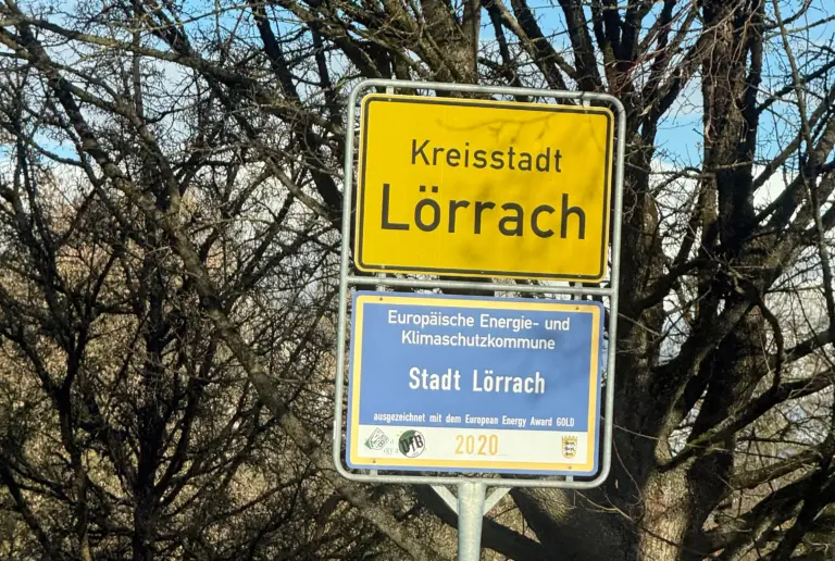 Yellow town sign reading 'Kreisstadt Lörrach' with a blue plaque below about European energy and climate protection municipality sign (city of Lörrach)