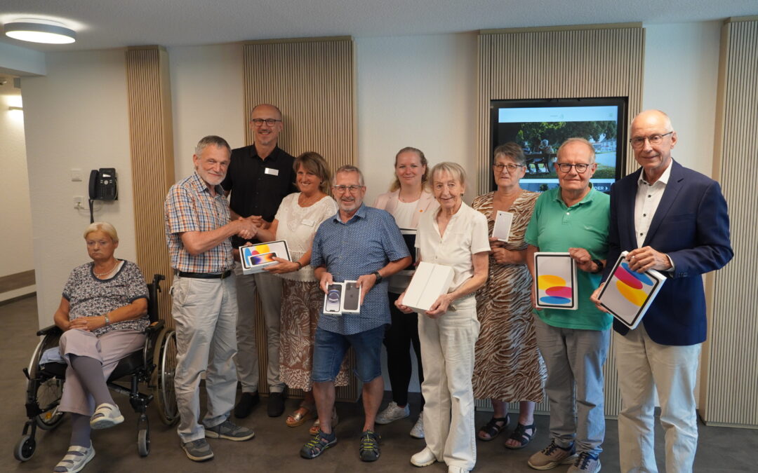 Group of eleven adults posing indoors for a photo; several hold iPhone boxes as prizes.