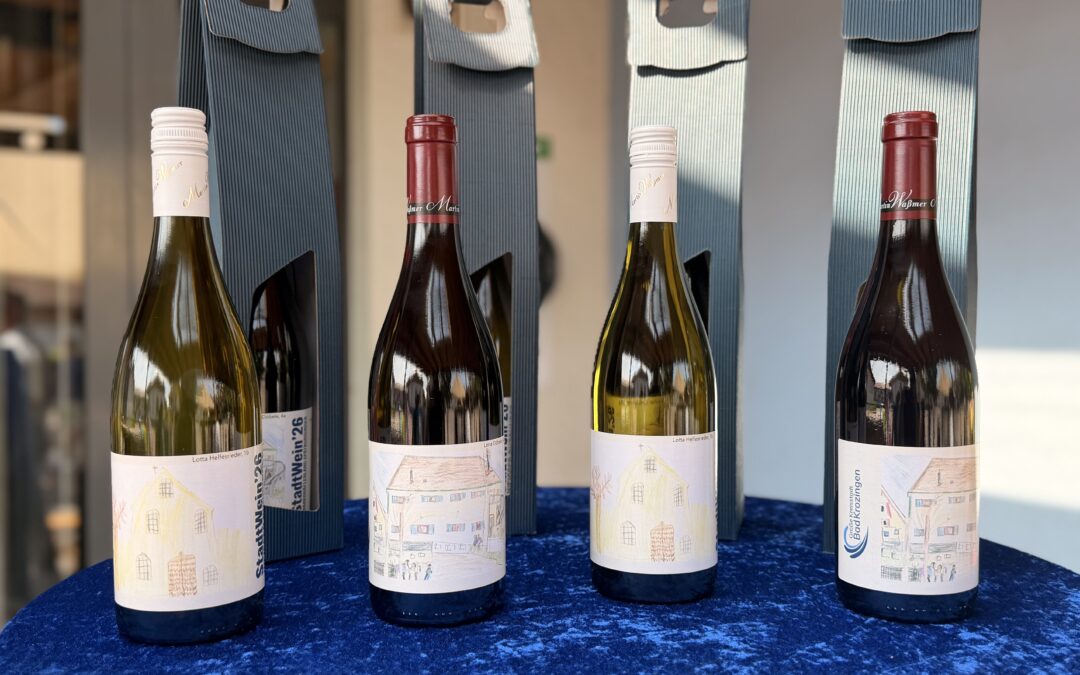 Row of wine bottles standing in blue gift-style boxes with handles and hand-drawn label wrappers on the bottles' lower portions on a blue surface.