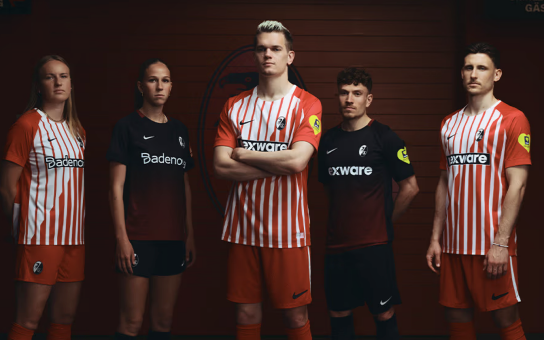 Five soccer players in red-and-white striped and black kits stand in a locker room, with the central player crossing his arms.