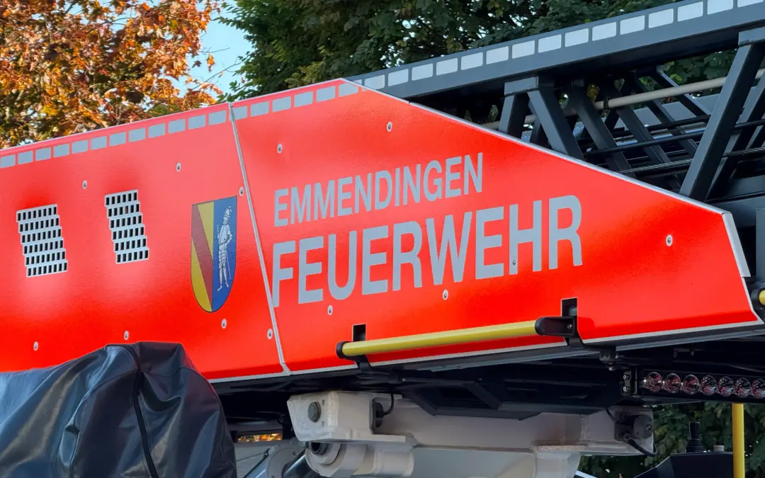 Close-up of a red fire service vehicle with a ladder and the word 'FEUERWEHR' visible, outdoors with trees in the background.