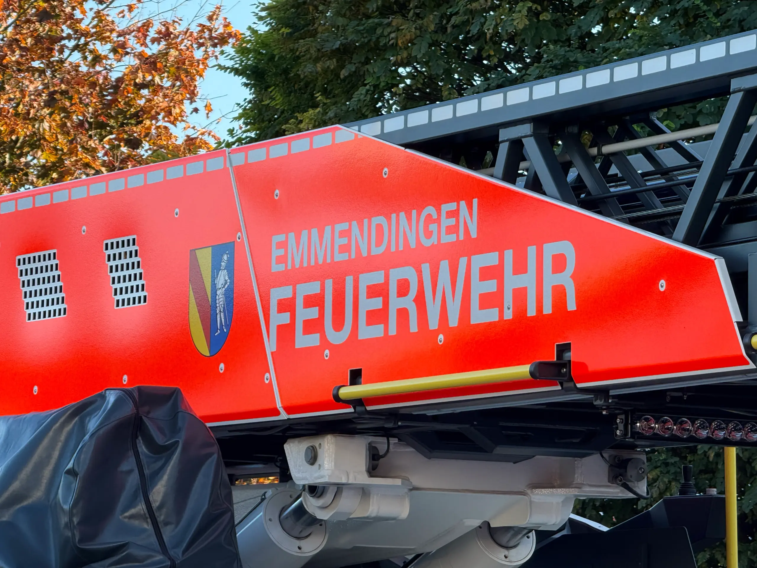 Close-up of a red fire service vehicle with a ladder and the word 'FEUERWEHR' visible, outdoors with trees in the background.