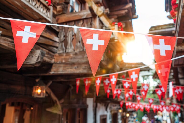 Red triangular bunting with white crosses strung across a rustic street.