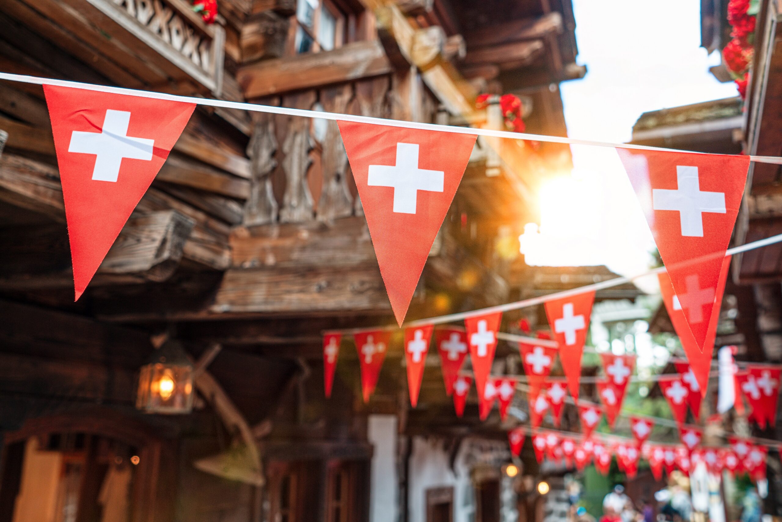 Red triangular bunting with white crosses strung across a rustic street.
