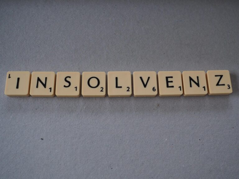 Row of Scrabble tiles spelling 'INSOLVENZ' on a gray surface.