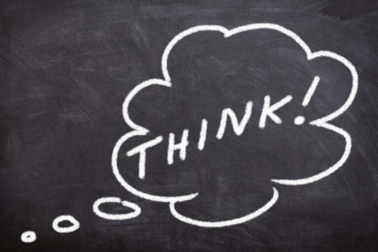 Chalk drawing of a thought bubble with the word THINK! on a dark chalkboard surface.