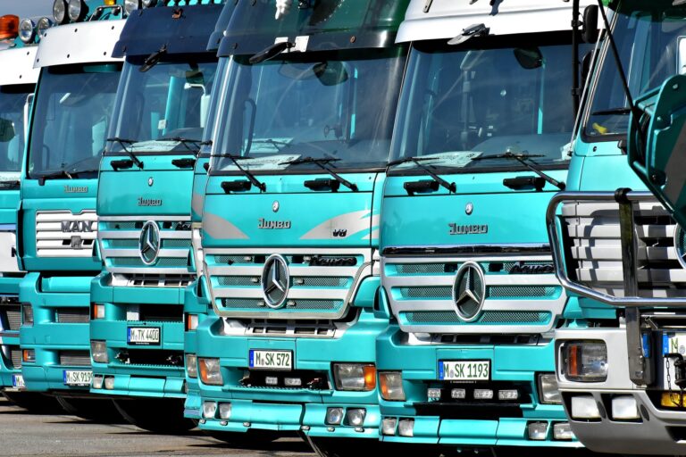 Row of turquoise truck cabs parked side by side, showing Mercedes-Benz logos and license plates