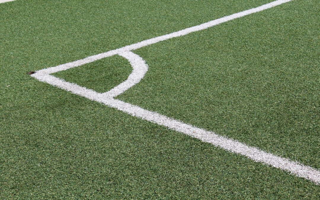 Close-up of artificial turf showing a white curved boundary line forming a corner on a sports field.